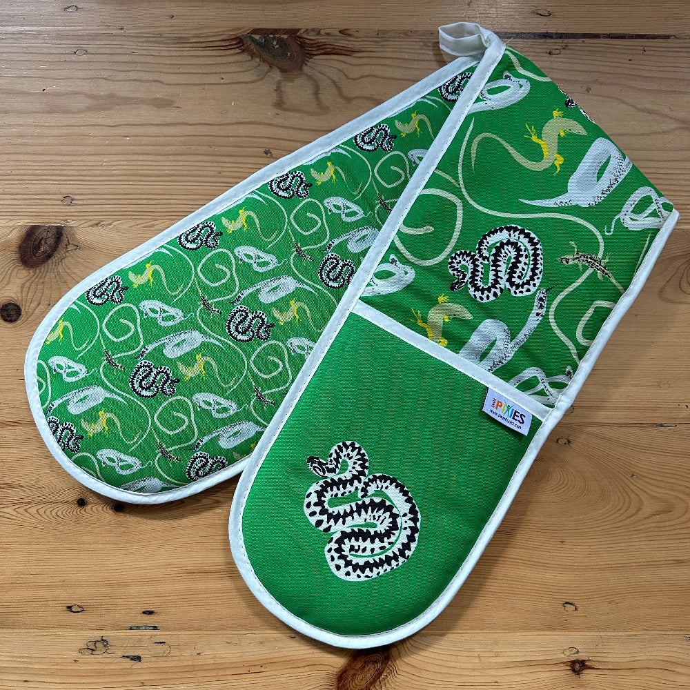 Green oven mitt and pot holder with snakes and lizards pattern on a wooden surface
