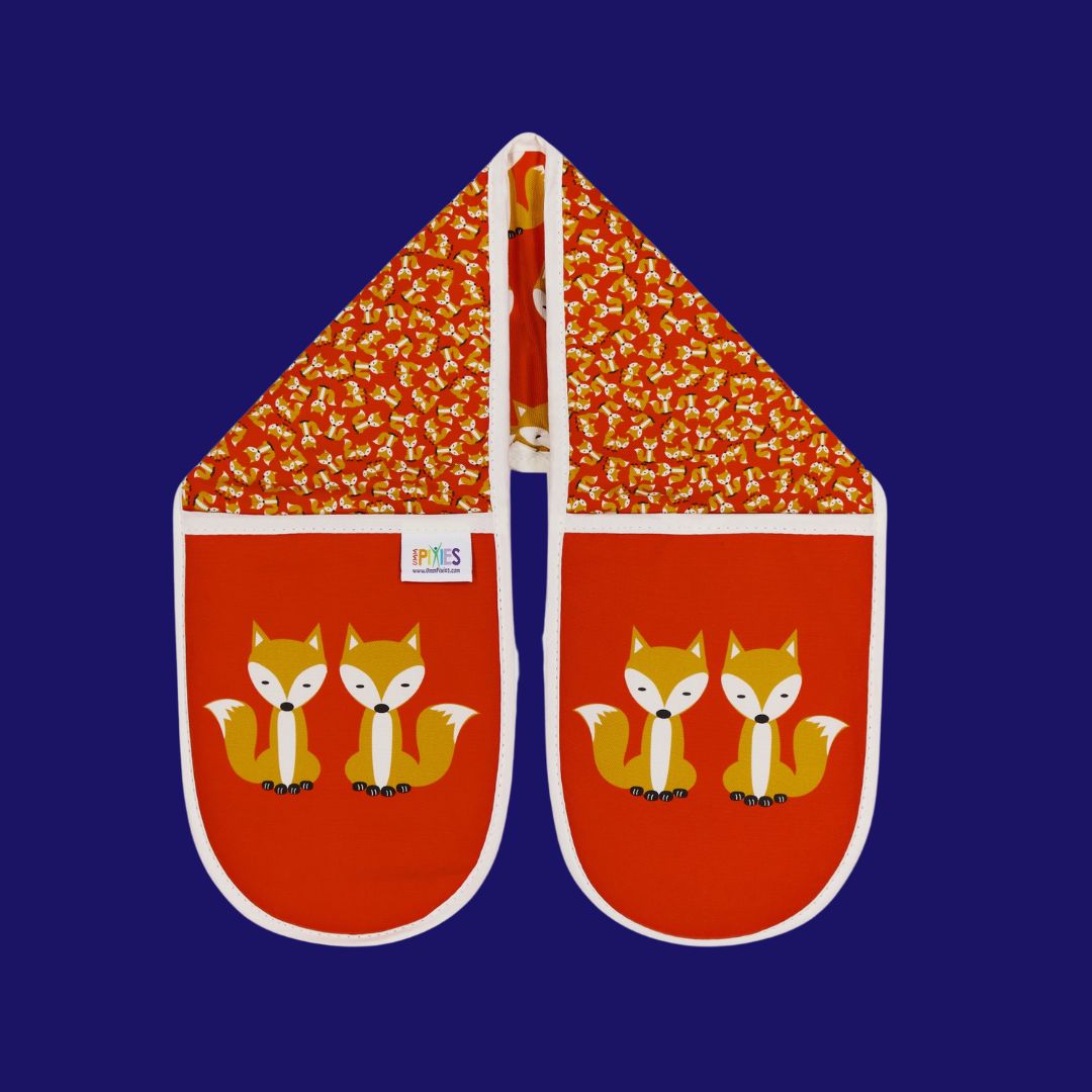 bright red colourful organic cotton oven gloves illustrated with fun fox design showing a parade of foxes on one side and a scatter of tiny foxes on the other. The main glove mitt features a bold print of a pair of sitting foxes