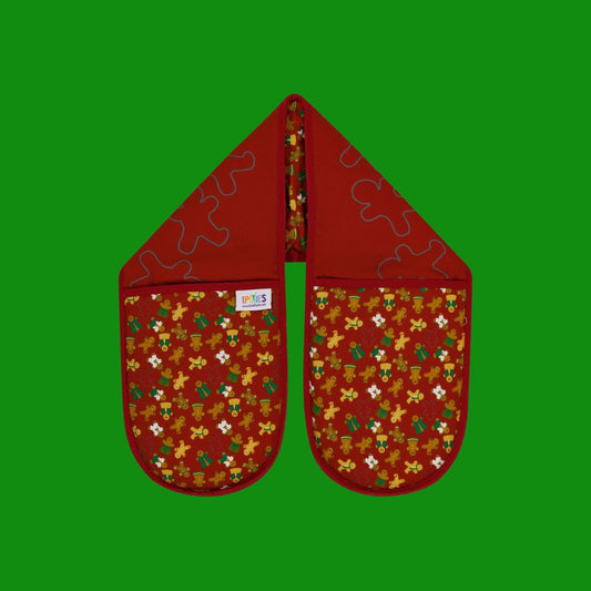Burgundy organic cotton double oven mitts with UmmPixies' gingerbread folk design. shown on a plain green background.