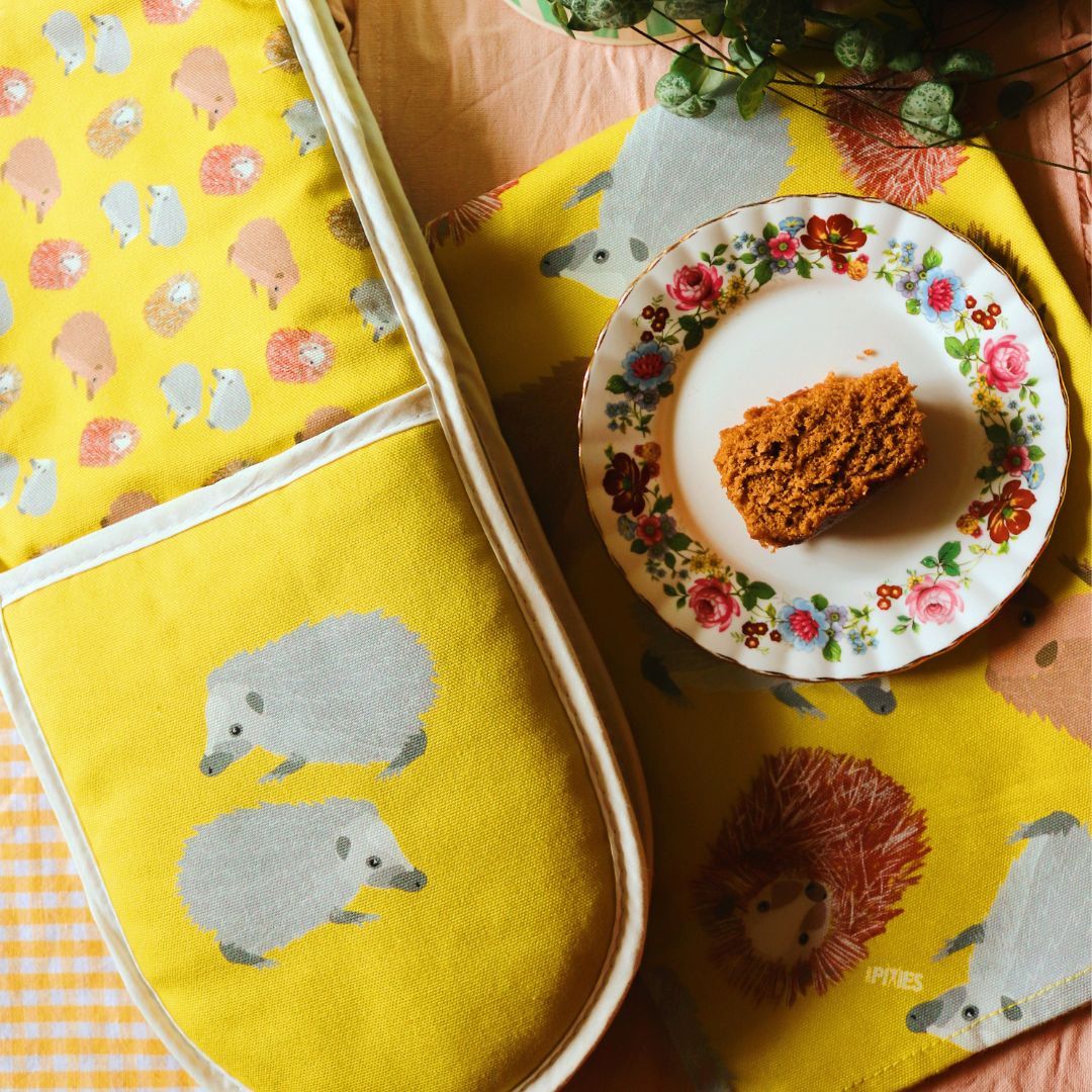 Hedgehog oven gloves and tea towel shown with freshly baked cake on plate Photo credit @rachelandthelittlebirds