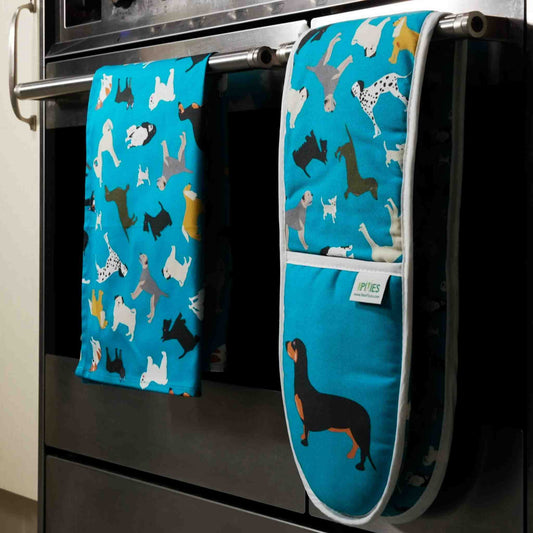 Blue dogs design oven mitts and matching tea towel shown hanging on a stove
