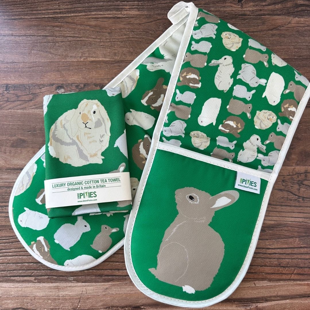Bright Green Rabbits design organic cotton Oven Mitts shown with matching tea towel on a wooden counter