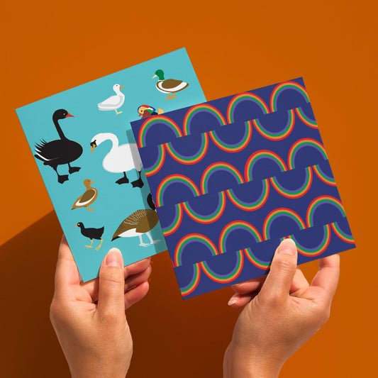 Rainbow stripe square greetings card shown held in hand with duck design card behind