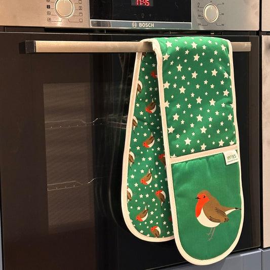 A green oven mitt with white star and robin patterns hanging from the handle of a Bosch built-in oven.
