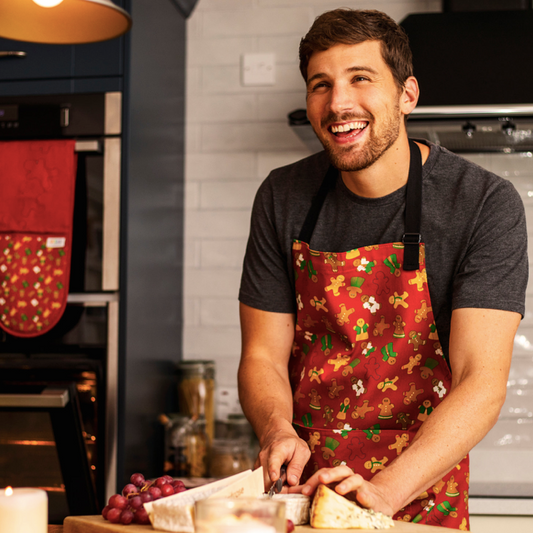Organic Cotton Gingerbread apron worn by male model, coordinating oven gloves in background.