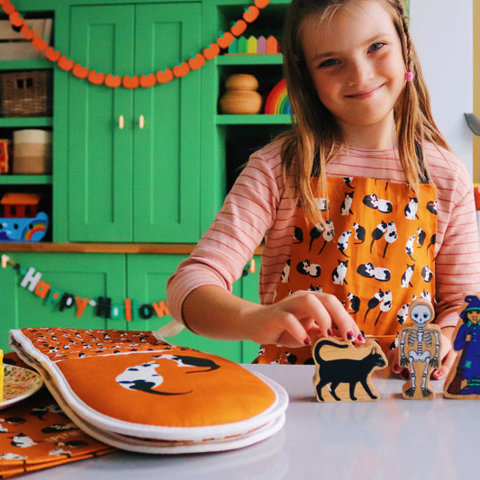 Child wearing Cats apron plays with halloween themed toys image credit Rachelandthelittlebirds
