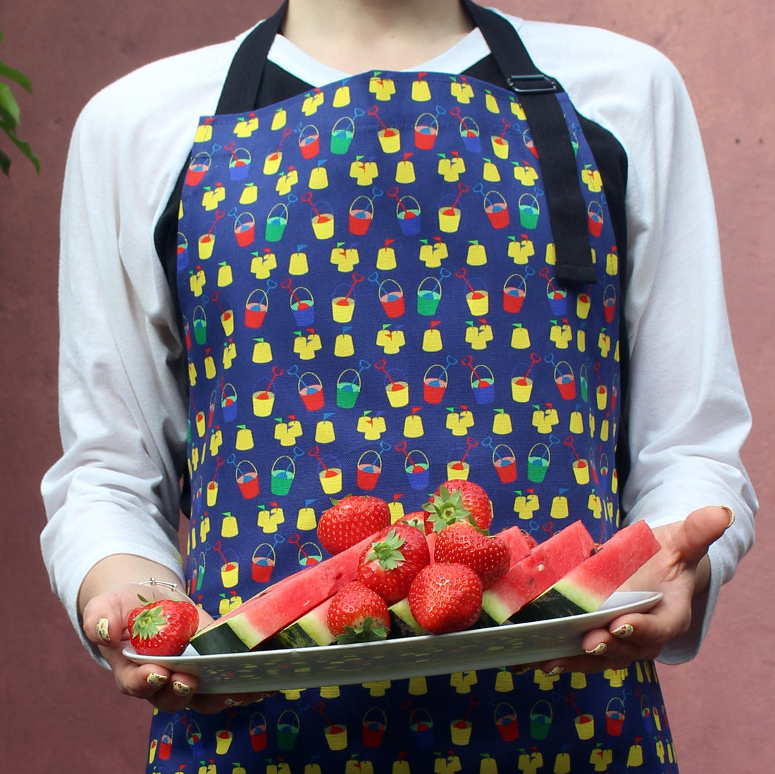 Model wears seaside apron and carries platter of fresh summer fruits