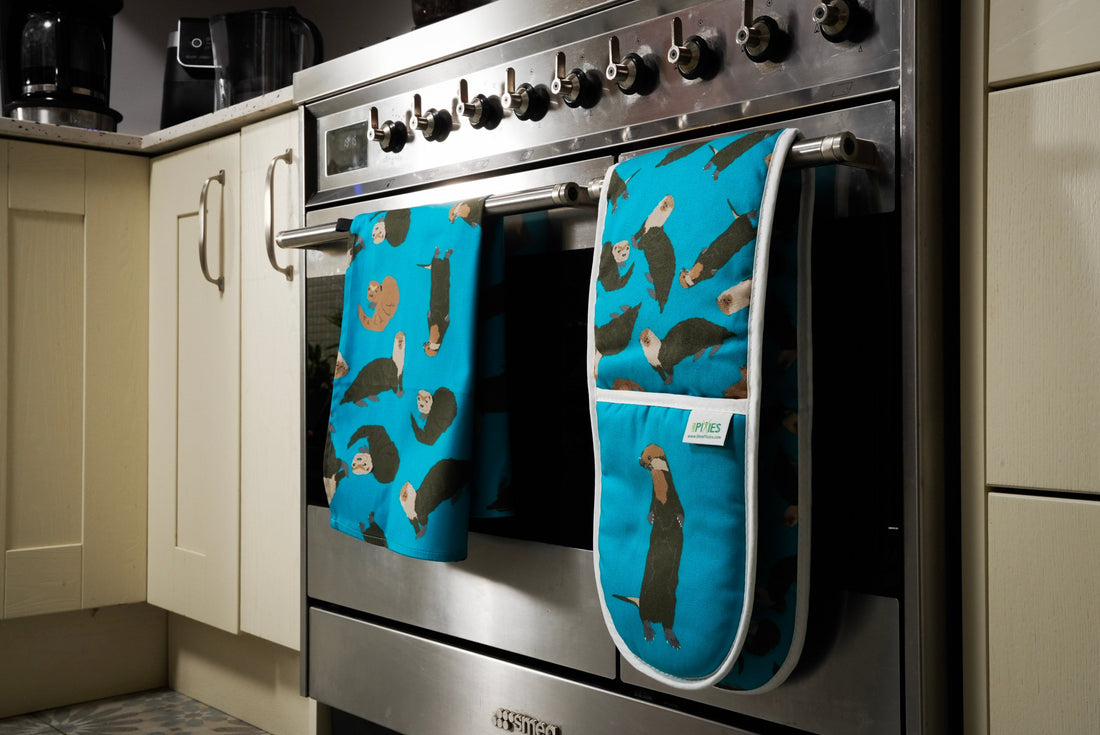Otter design oven gloves and tea towel hanging on a stove door