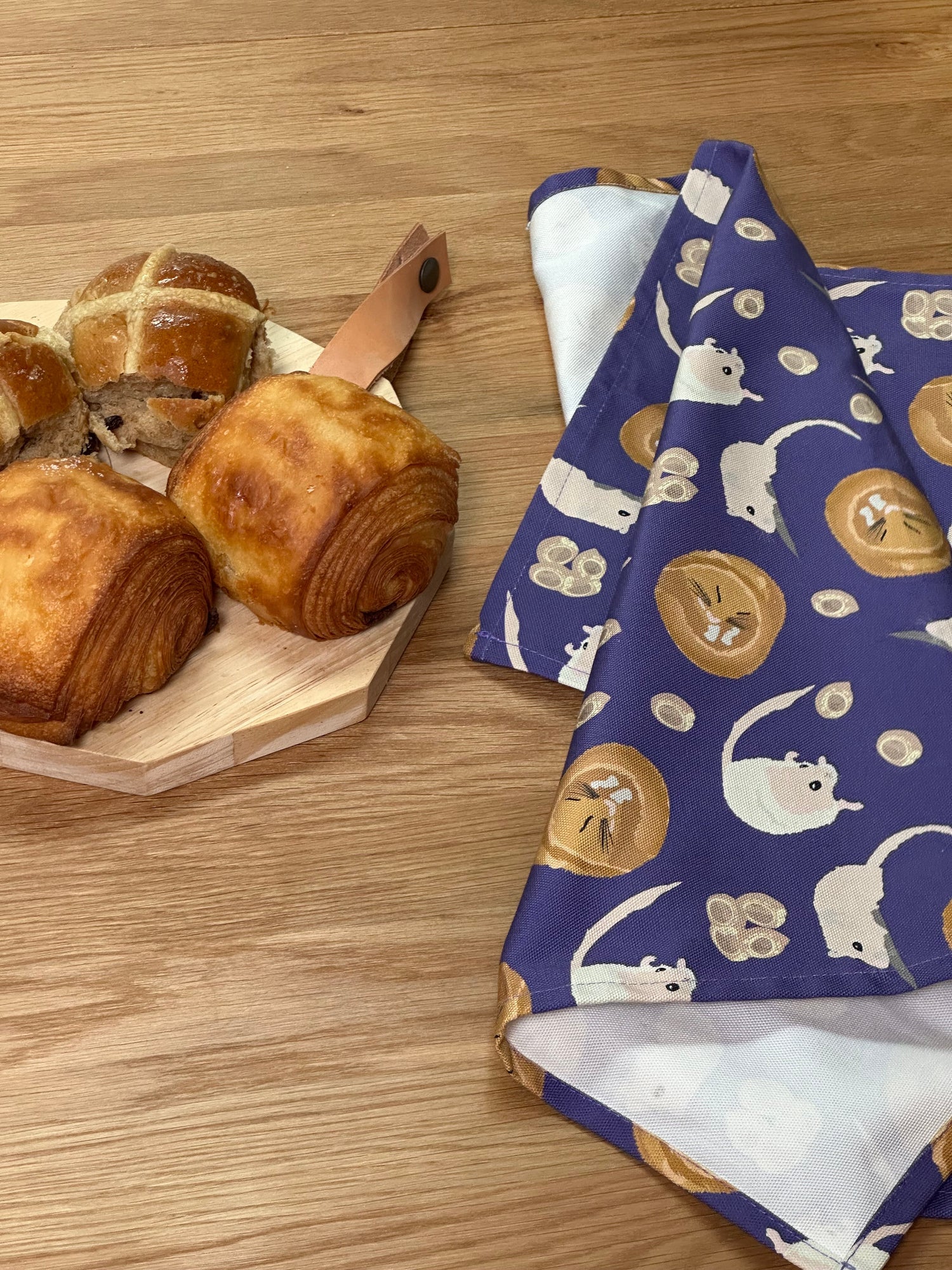 Dormouse design tea towel shown next to a board of pastries