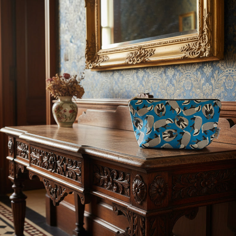Bright blue zipped pouch with badger pattern shown on a hallway console table