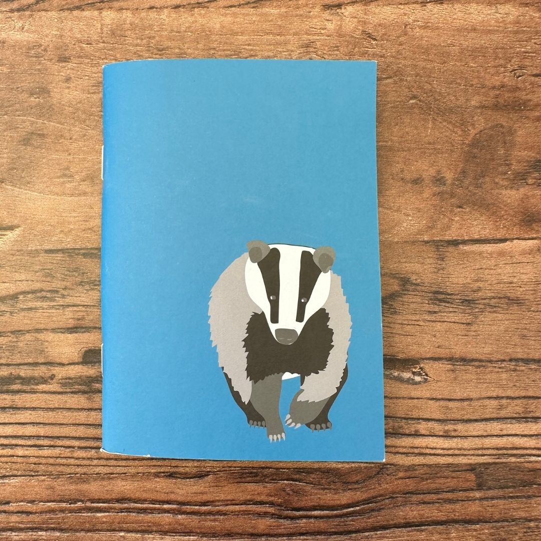 Blue notebook with a badger illustration on a wooden surface