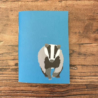 Blue notebook with a badger illustration on a wooden surface