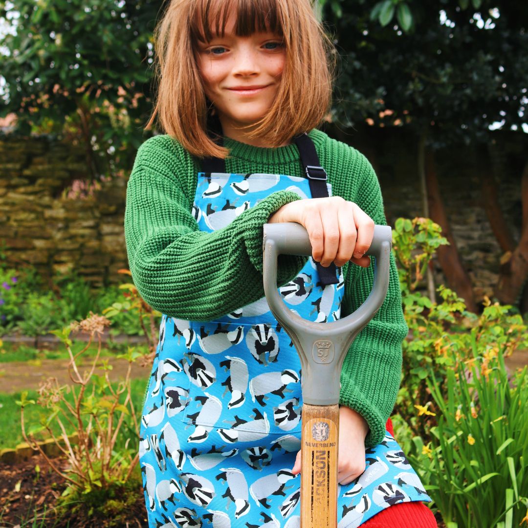 Badger younger child up to 5 years apron shown worn by child gardening . Photo credit @rachelandthelittlebirds