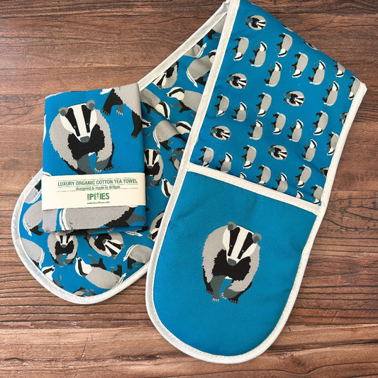 Blue oven mitt and pot holder with badger pattern on a wooden surface