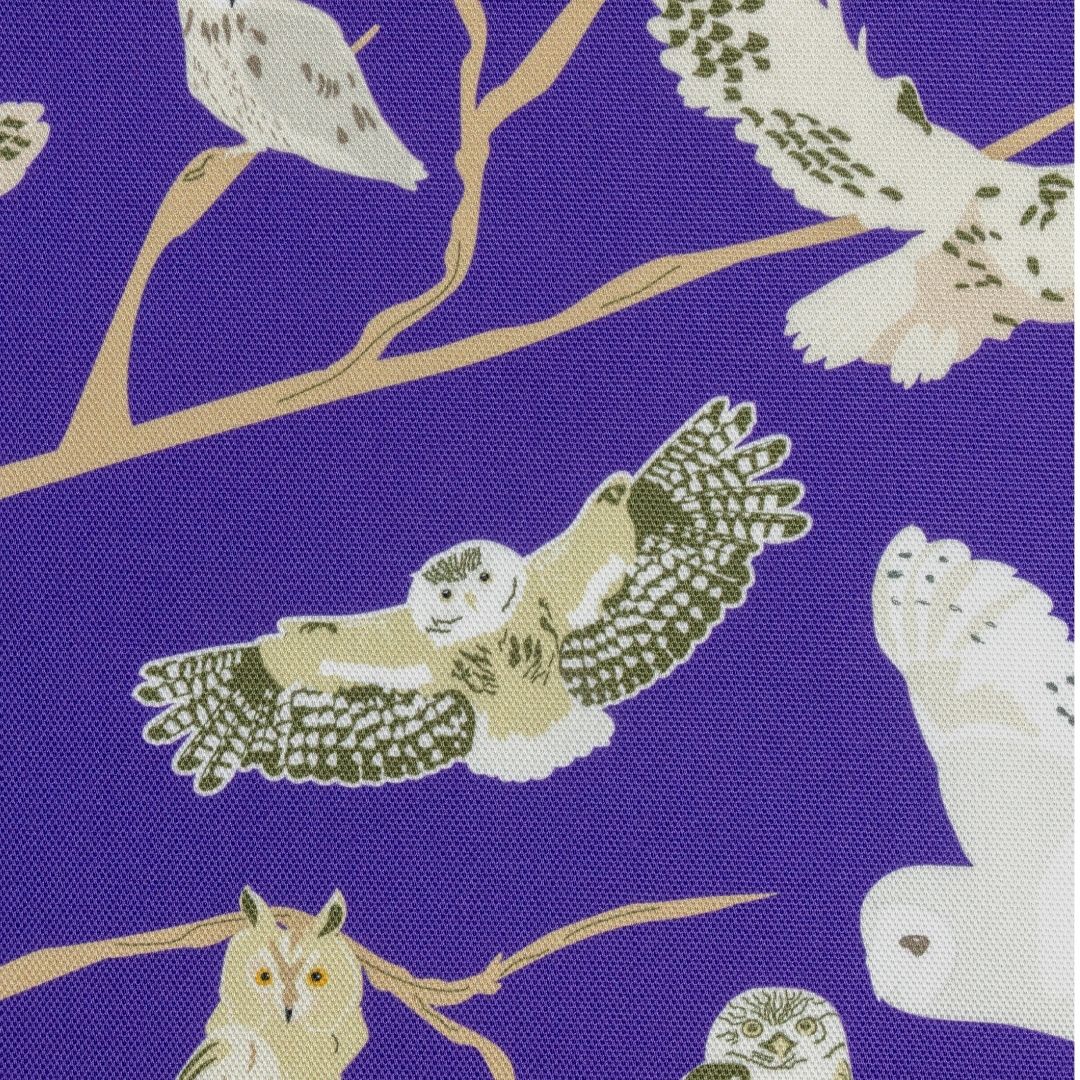 Close up of a purple organic cotton tea towel with pattern featuring the 5 species of native British owls. Great gift for bird lovers and wildlife fans, illustrations include the barn owl, tawny owl and more