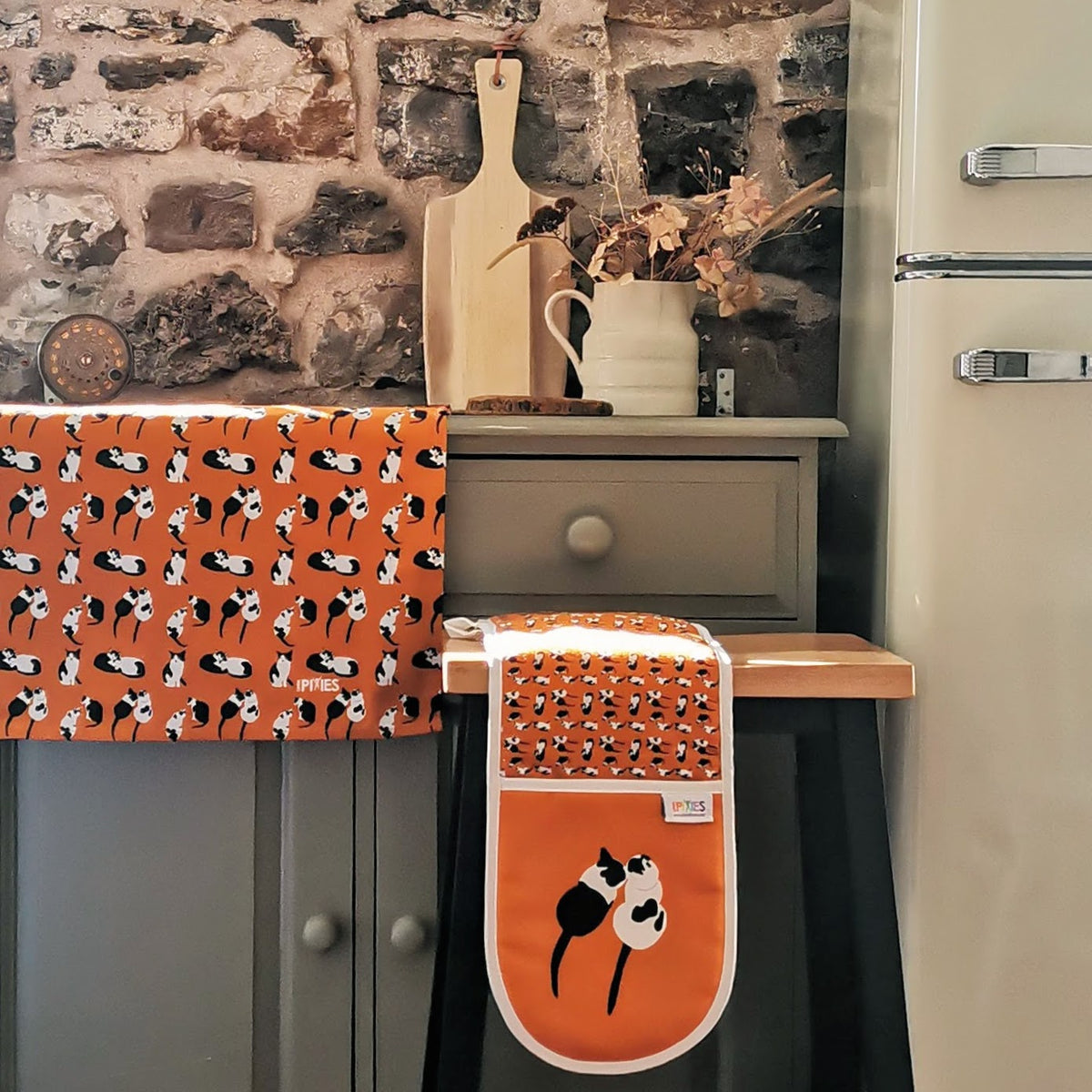 Cats design tea towel and oven gloves  shown in a rustic kitchen