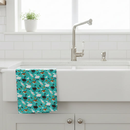 Kitchen sink with a colourful towel featuring illustrations of ducks swans geese and more  hanging on the side.
