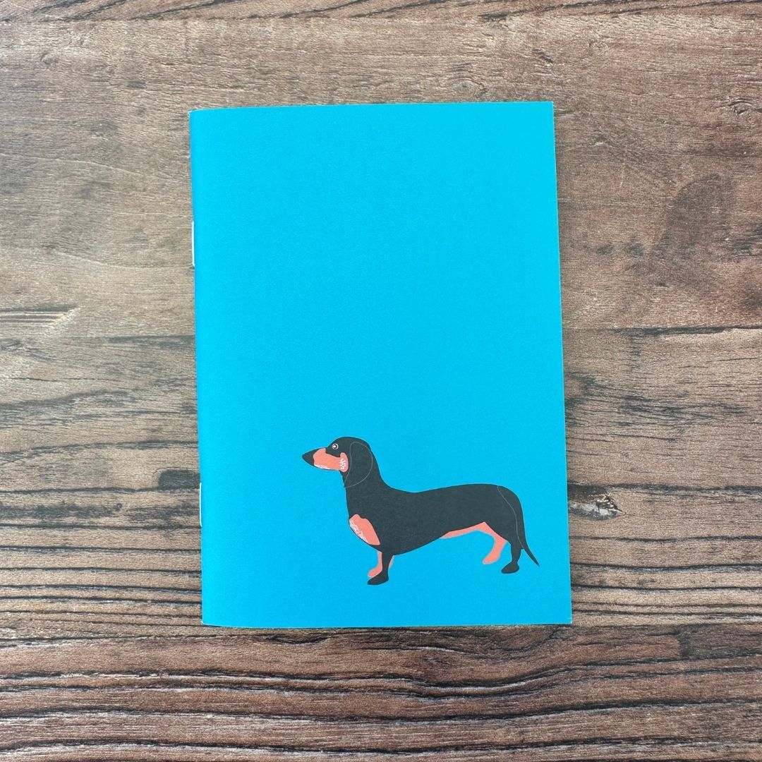 Blue notebook with a dachshund illustration on a wooden surface