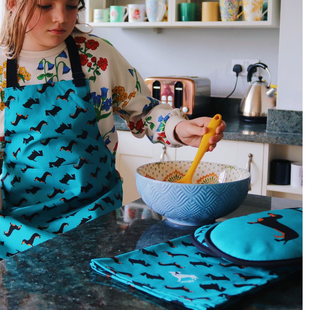 Older child wearing apron and baking with tea towel and ovengloves visible in front of image Photo credit: @rachelandthelittlebirds