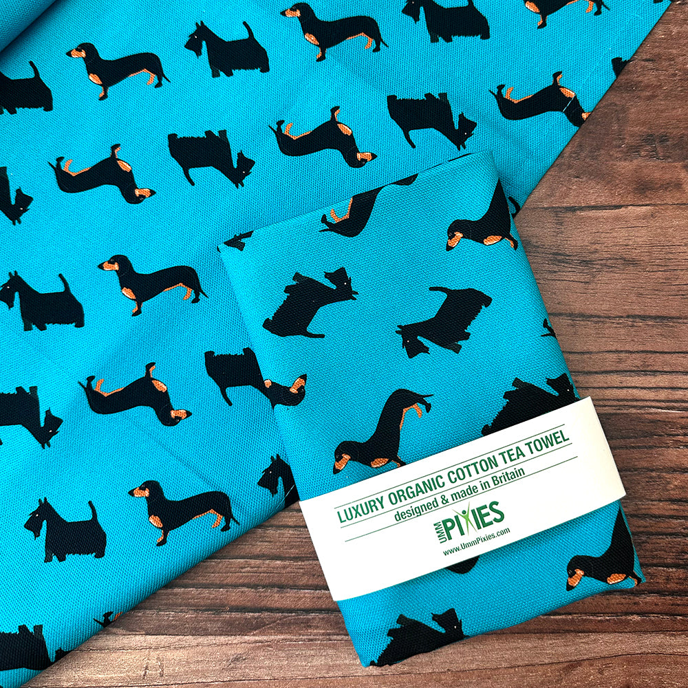organic cotton petrol blue dogtooth dogs tea towel featuring daschund, Scottish terrier and black and white rescue dog shown in UmmPixies bran packaging