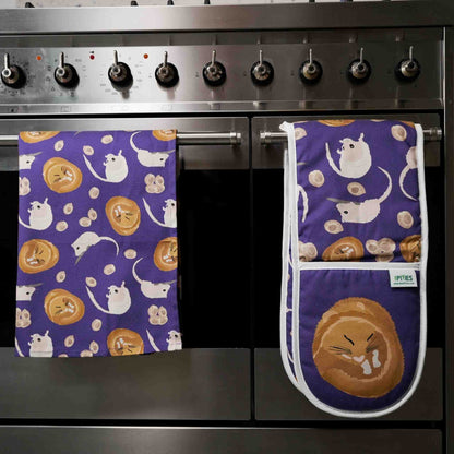 purple cotton kitchen towels and matching oven gloves with dornouse patterns hanging on a stove.