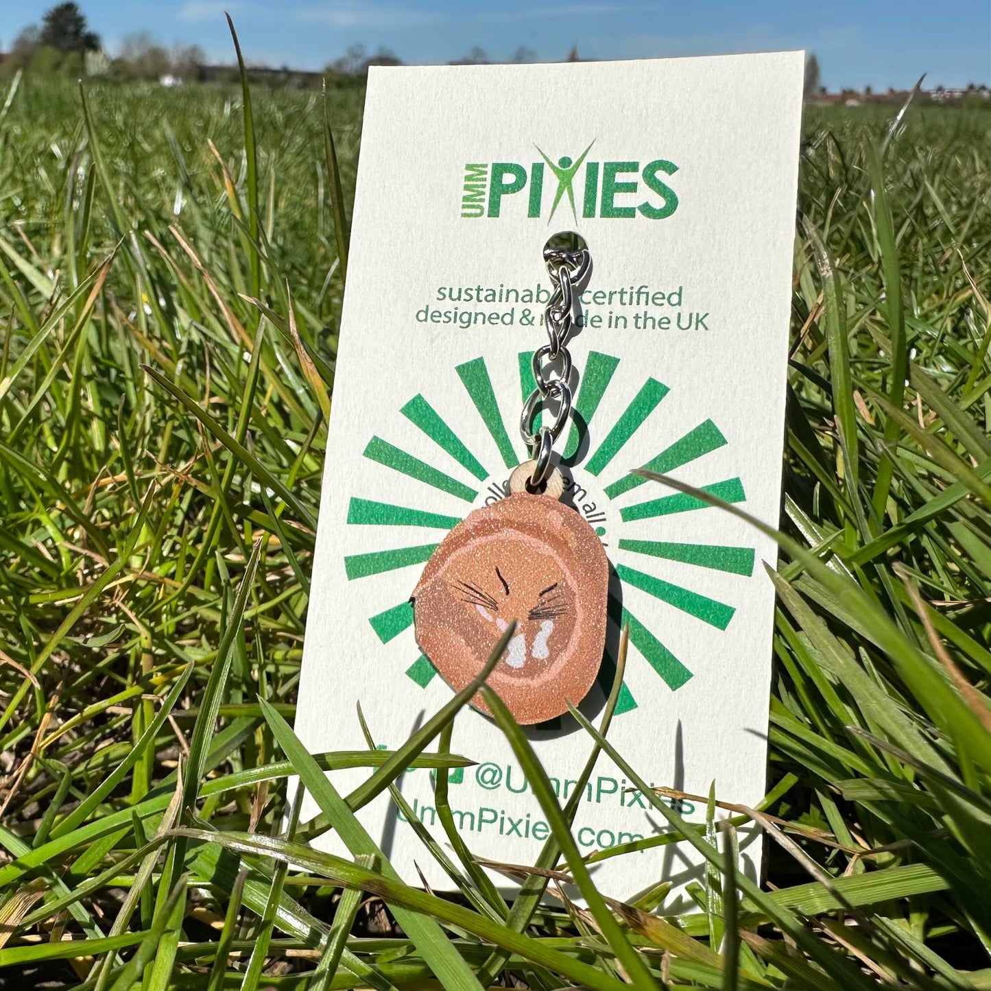 Dormouse Keychain  on a white retail packaging card in grass.
