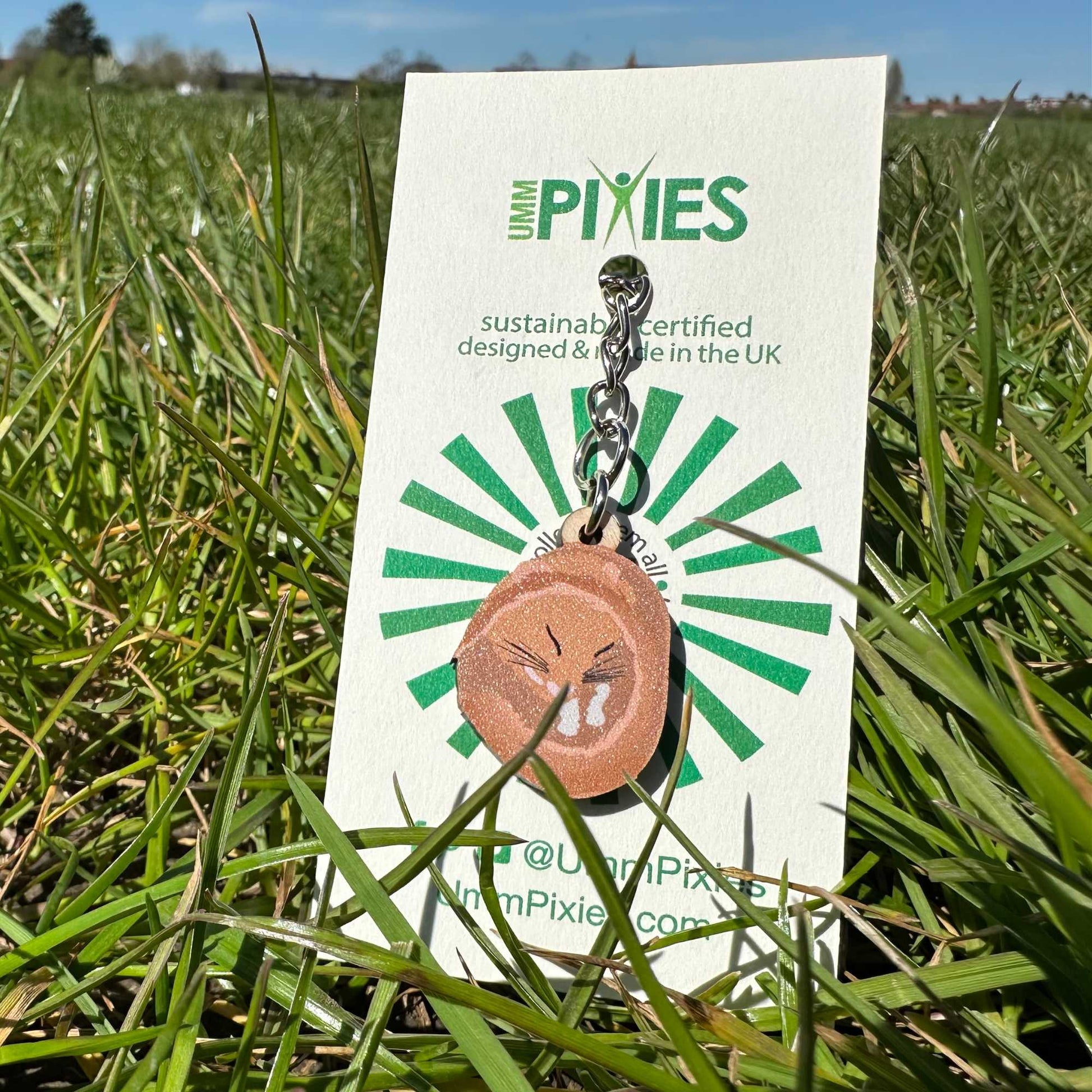 Dormouse Keychain  on a white retail packaging card in grass.