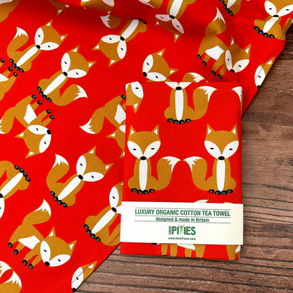 Red foxes luxury organic cotton tea towel with fox pattern on a wooden surface