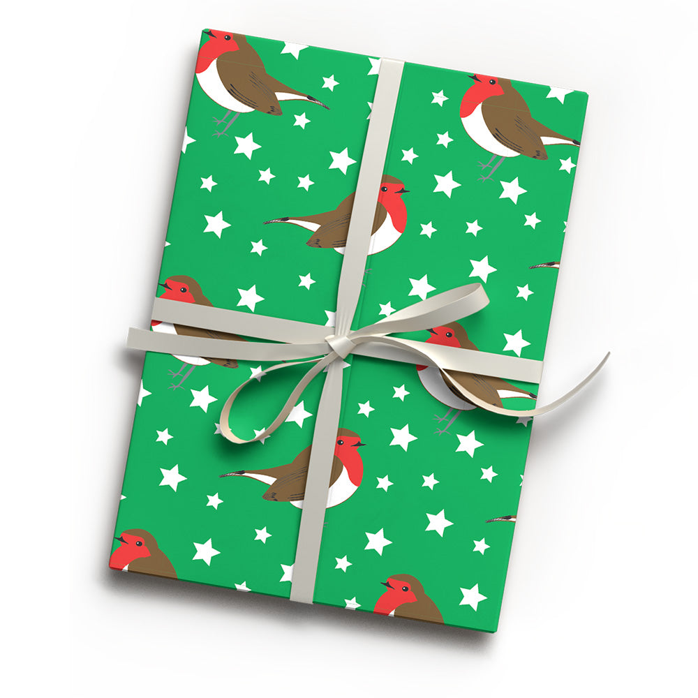Gift wrapped in green wrapping paper with repeating pattern of robin redbreasts and white stars and tied with a bow of ribbon