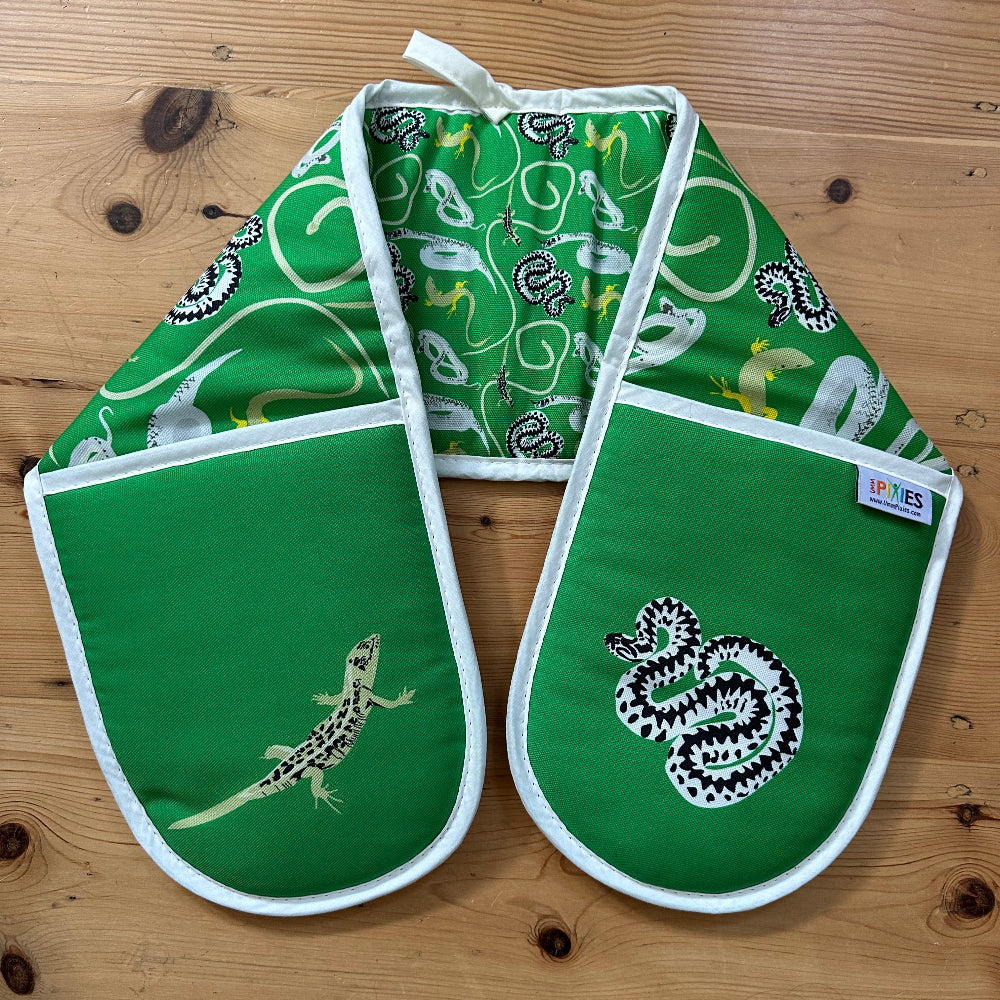 Green oven mitts with lizard pattern on a wooden surface