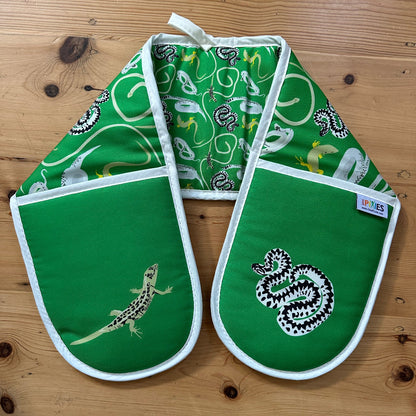 Green oven mitts with lizard pattern on a wooden surface
