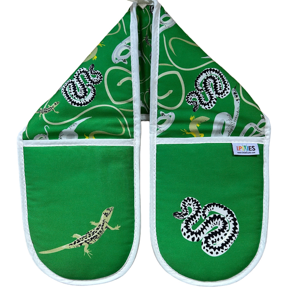 Green oven mitts with snakes and lizards patterns on a wooden surface