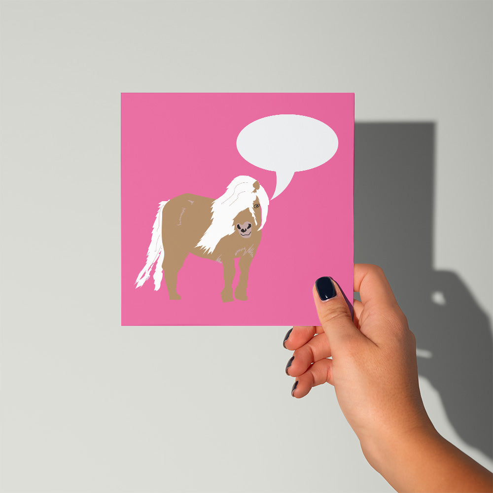 Hand holding a pink card with a horse illustration and speech bubble on a gray background