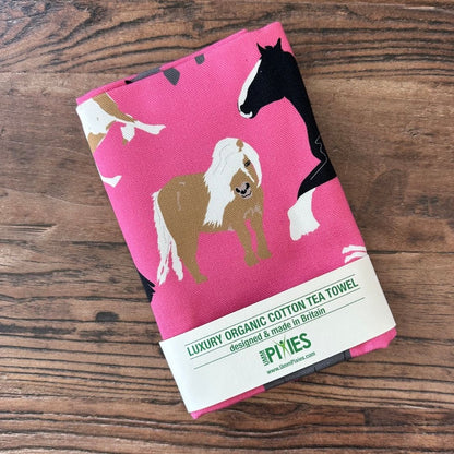 Bright Pink Horses illustrations organic cotton tea towel on a wooden counter
