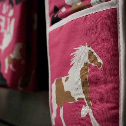 Pink oven gloves with horse illustrations: close up image of them hanging on a stove