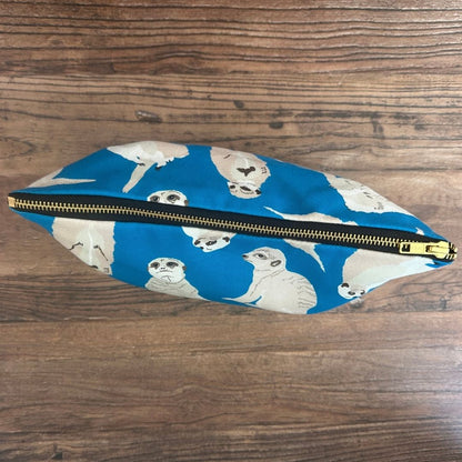 Bright blue Meerkats illustrated really useful bag shown from above with zip closed on a wooden surface