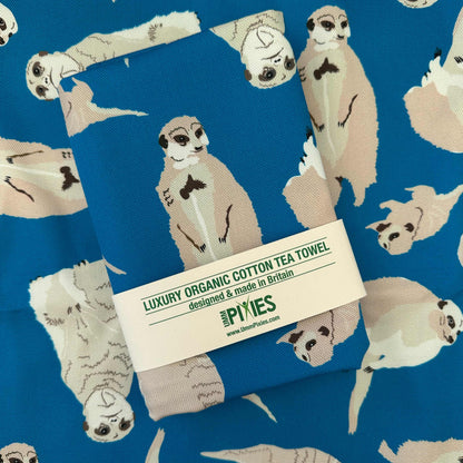 Luxury organic cotton tea towel with meerkat pattern shown in retail packaging on a open example of the tea towel