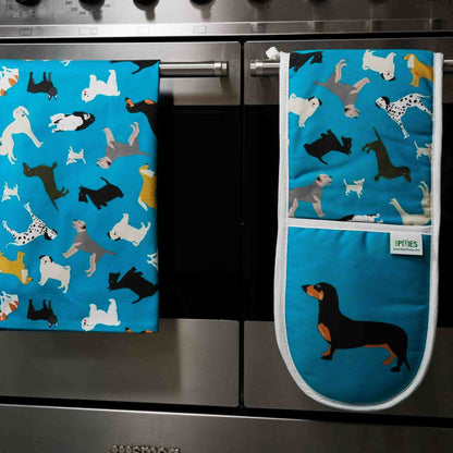 Blue kitchen towel and oven mitt with dog pattern hanging on a stove.