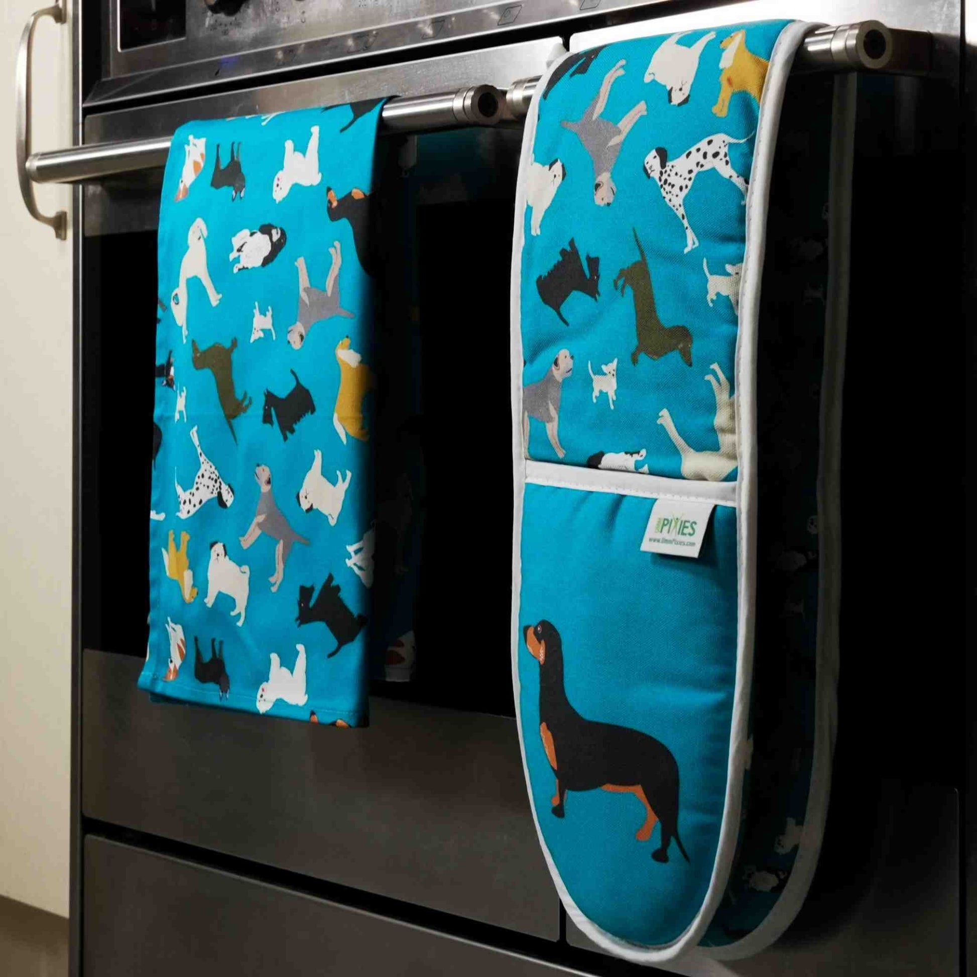 Blue dogs design oven mitts and matching tea towel shown hanging on a stove