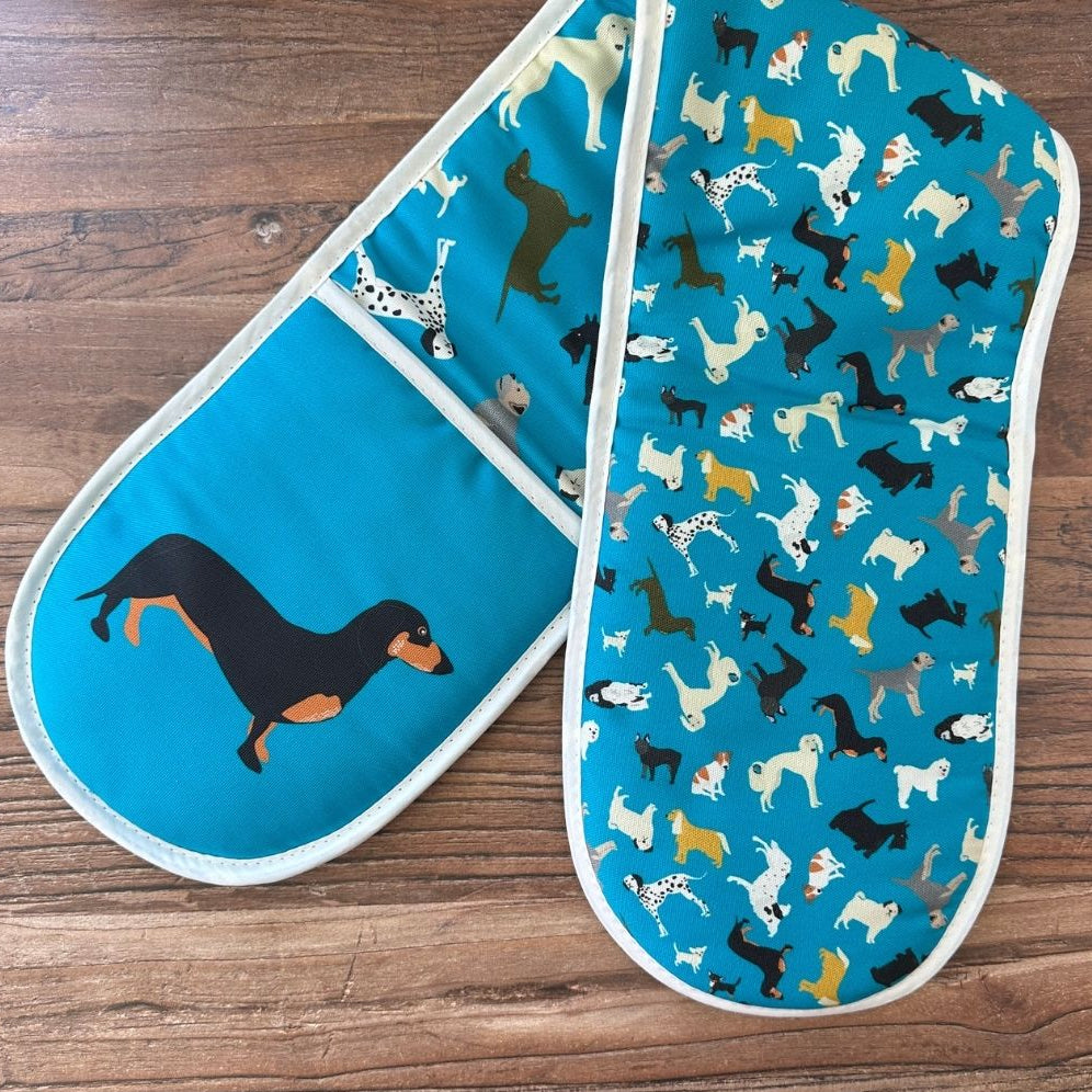 Petrol blue organic cotton colourful oven mitts with dog pattern on a wooden surface showing pattern on reverse