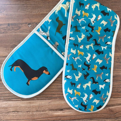 Petrol blue organic cotton colourful oven mitts with dog pattern on a wooden surface showing pattern on reverse
