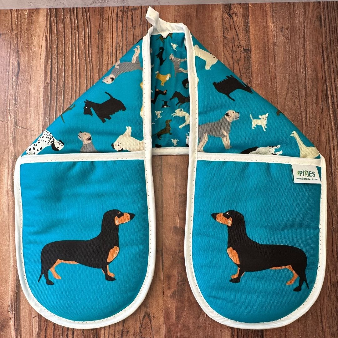 Petrol blue organic cotton colourful oven mitts with dog pattern on a wooden surface