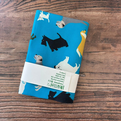 Petrol Blue New Tricks Dogs design organic cotton tea towel on a wooden counter