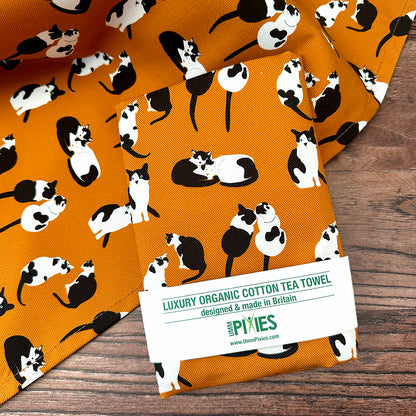 Orange tea towel with black and white cat pattern shown open and in packaging 