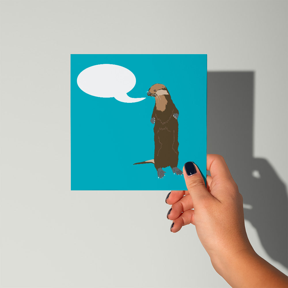 Hand holding a card with an otter illustration and speech bubble on a blue background