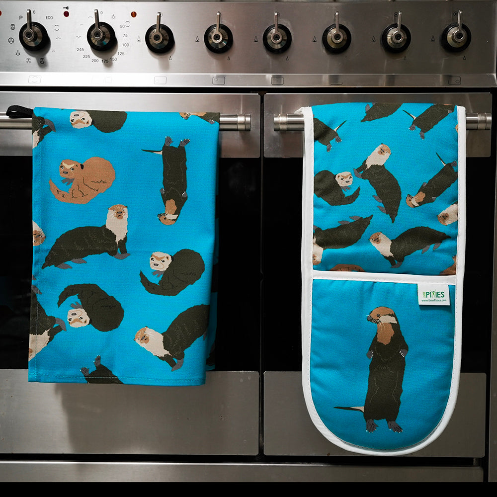 Bright petrol blue Otter oven gloves and tea towel shown draped over oven door handles