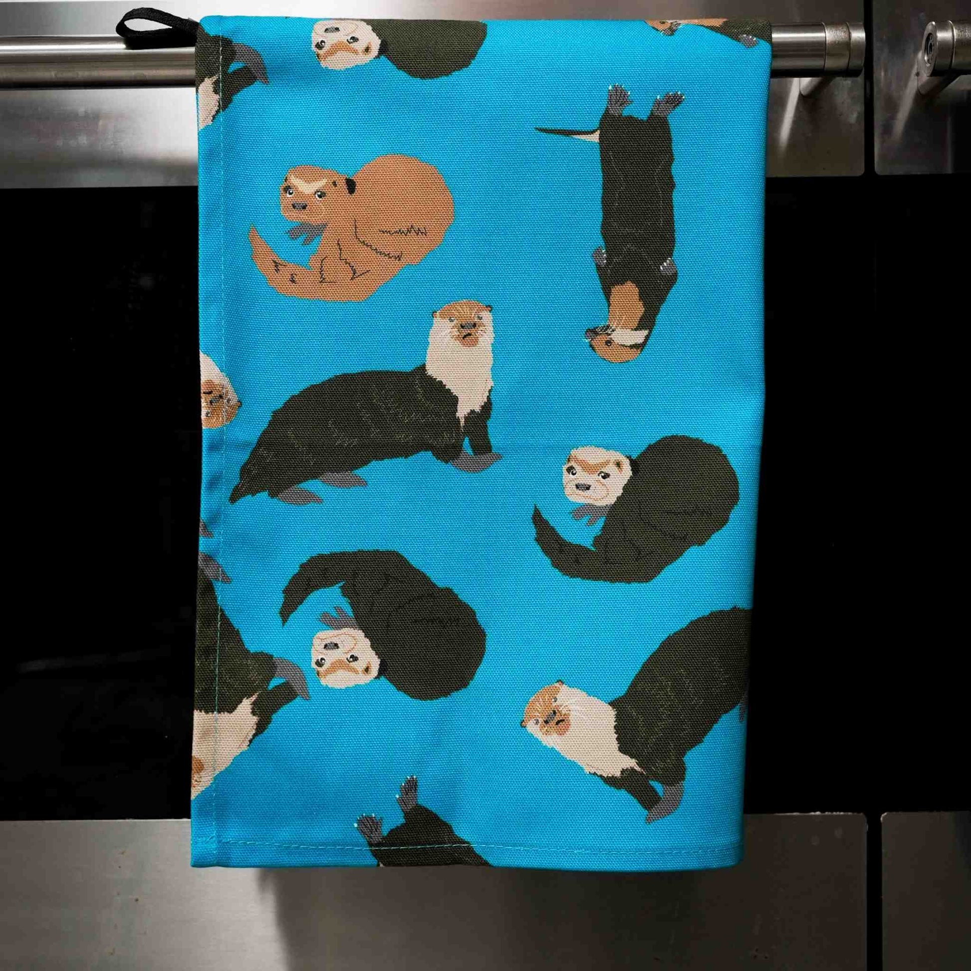 Towel with otter pattern hanging on a stove front