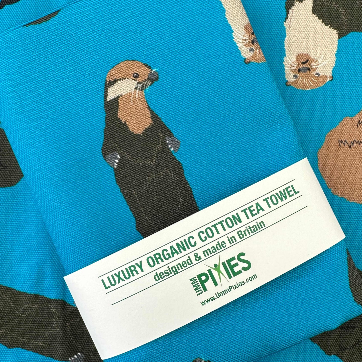 Blue Tea towel with otter design shown in retail packaging