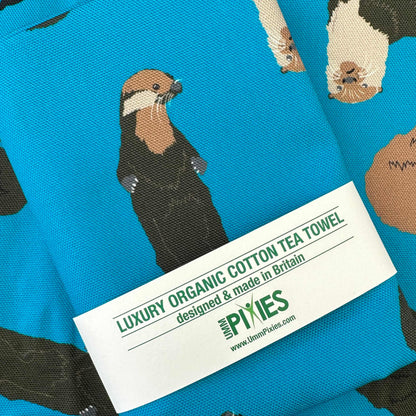 Blue Tea towel with otter design shown in retail packaging