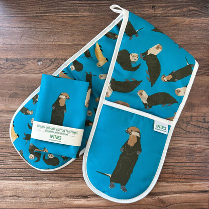 Tea towel and oven mitt with otter pattern on a wooden surface